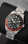 angled top-down studio view of the stainless steel Tudor Black Bay 58 GMT watch showing its gilt-accented black dial and rivet bracelet