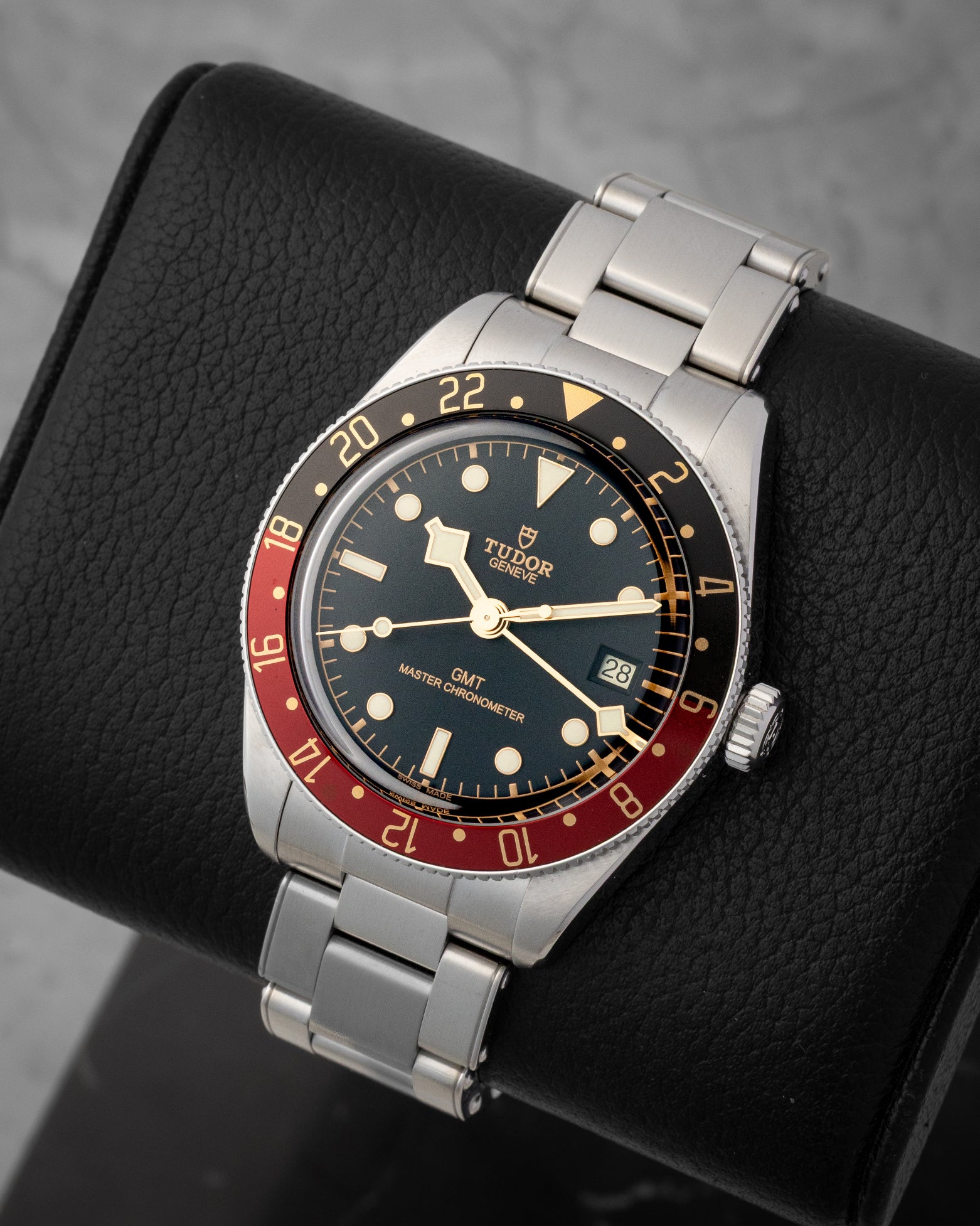 angled top-down studio view of the stainless steel Tudor Black Bay 58 GMT watch showing its gilt-accented black dial and rivet bracelet