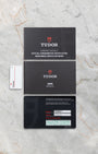The official Tudor international warranty card, chronometer certification booklet, and user manual laid out on a marble surface