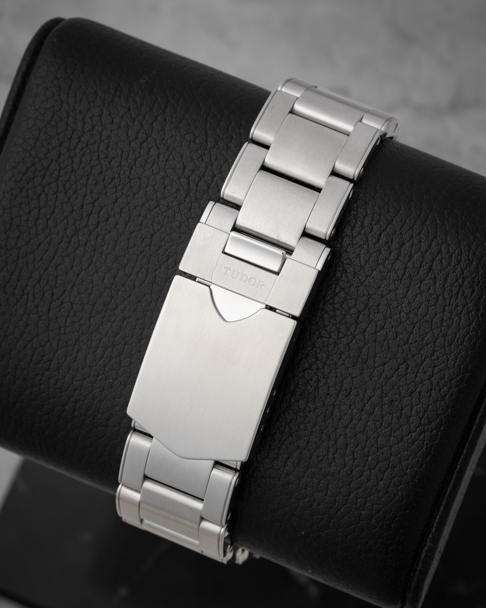 rear snapshot focusing on the brushed stainless steel three-link rivet-style bracelet and the folding safety clasp closure