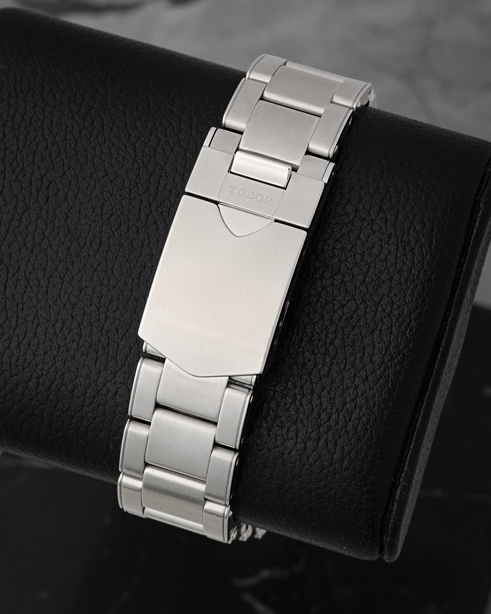 A rear view of the three-row stainless steel oyster link bracelet focusing on the secure closure of the satin-brushed folding deployment buckle detailed with a polished Tudor shield safety latch