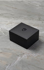 angled overview of the closed, textured black Tudor luxury watch presentation box sitting on a stone studio surface
