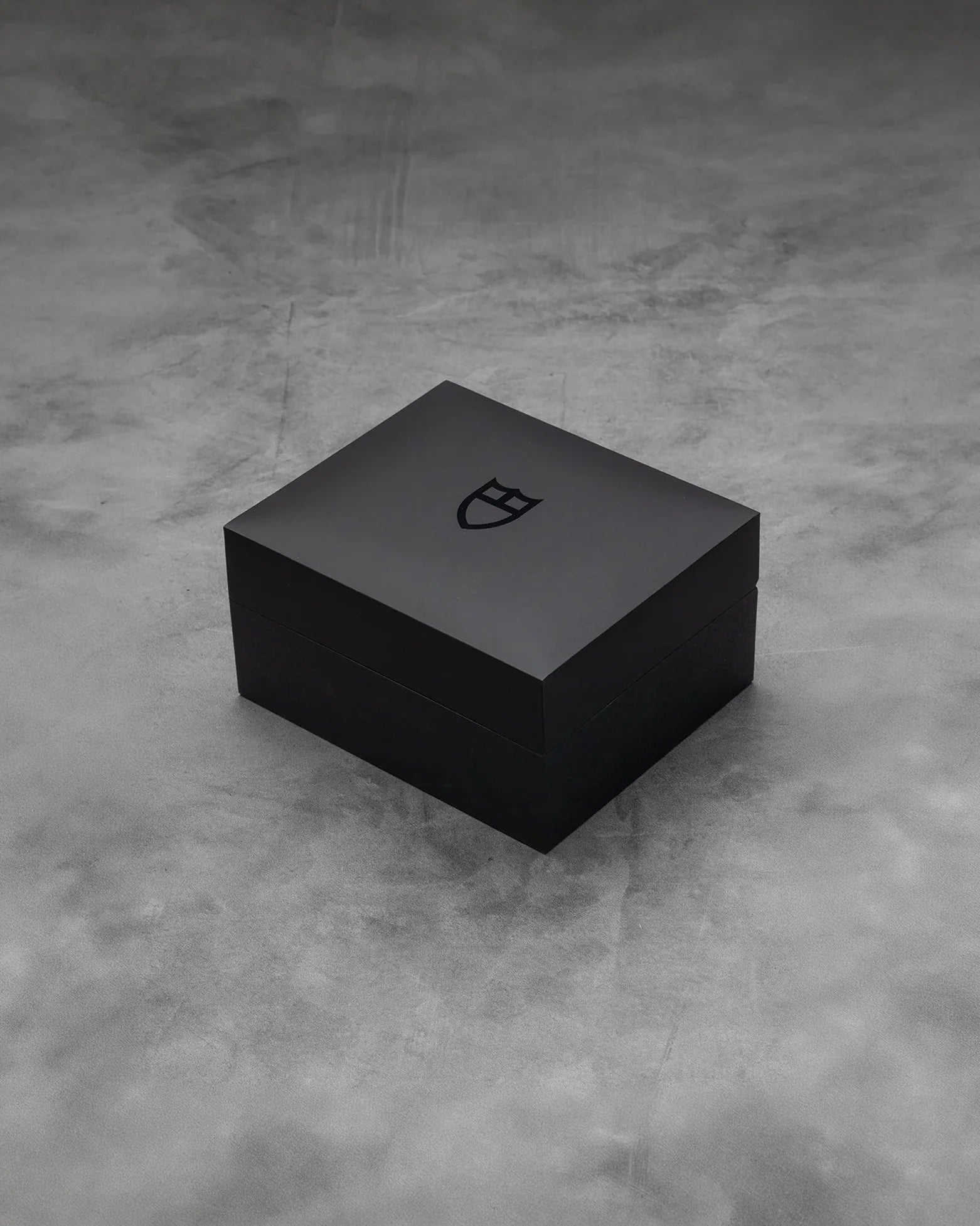 Official minimalist textured matte black square Tudor presentation watch box sitting on marble