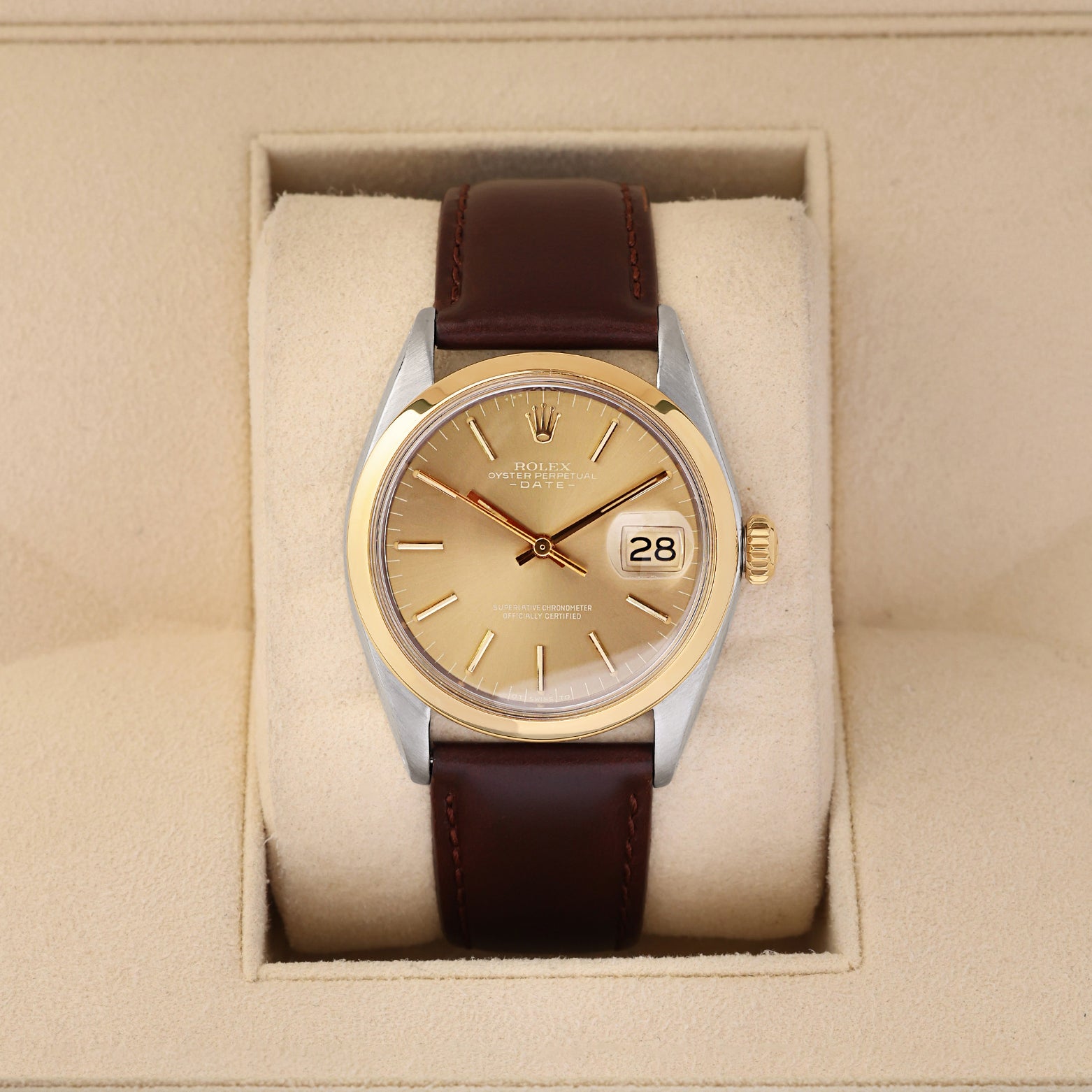A vintage 1969 Rolex Oyster Perpetual Date reference 1500 featuring a champagne sunburst dial, smooth 14k yellow gold bezel, and a brown leather strap inside its display box at Noah's Fine Watches & Jewelry in Dallas