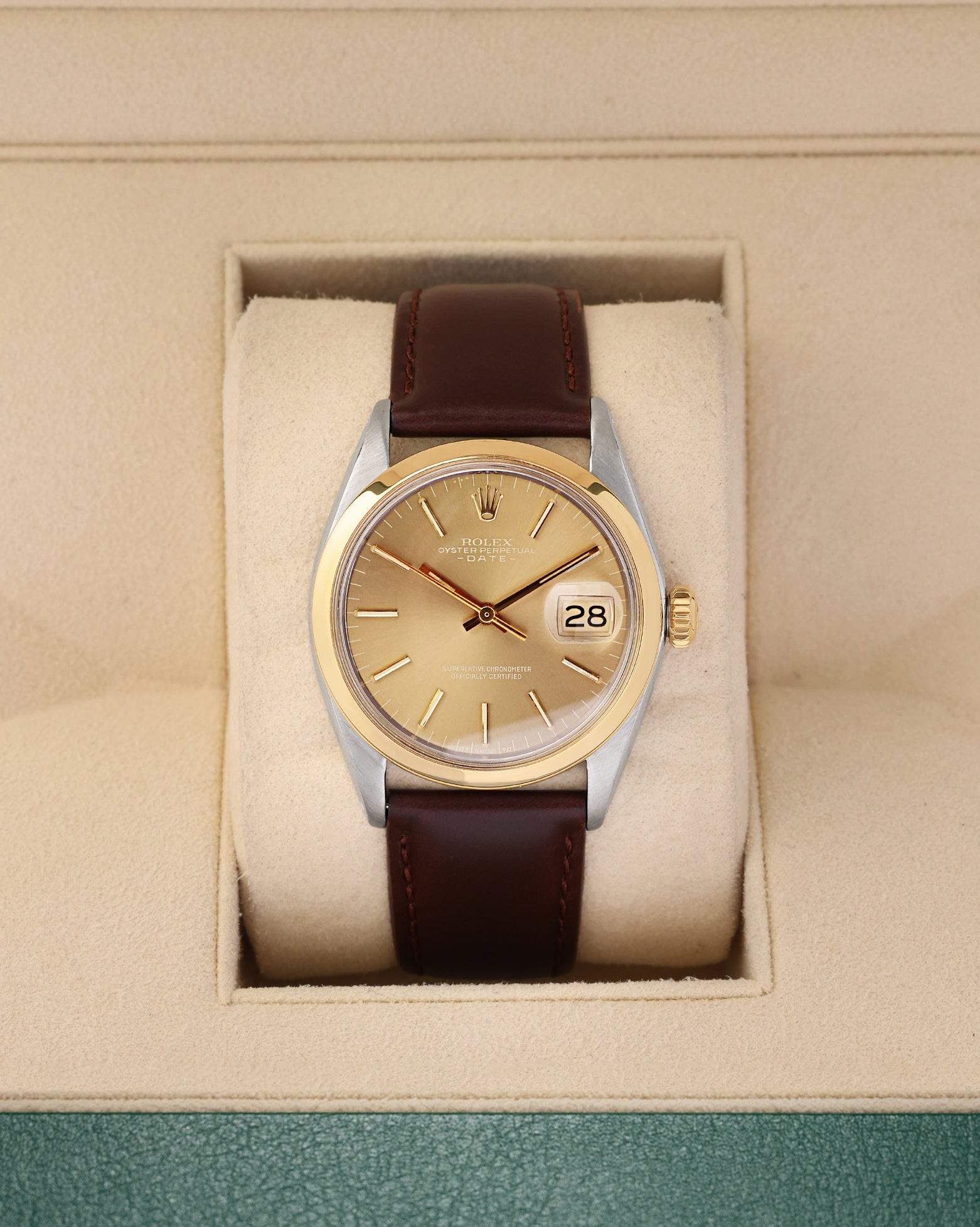A vintage 1969 Rolex Oyster Perpetual Date reference 1500 featuring a champagne sunburst dial, smooth 14k yellow gold bezel, and a brown leather strap inside its display box at Noah's Fine Watches & Jewelry in Dallas