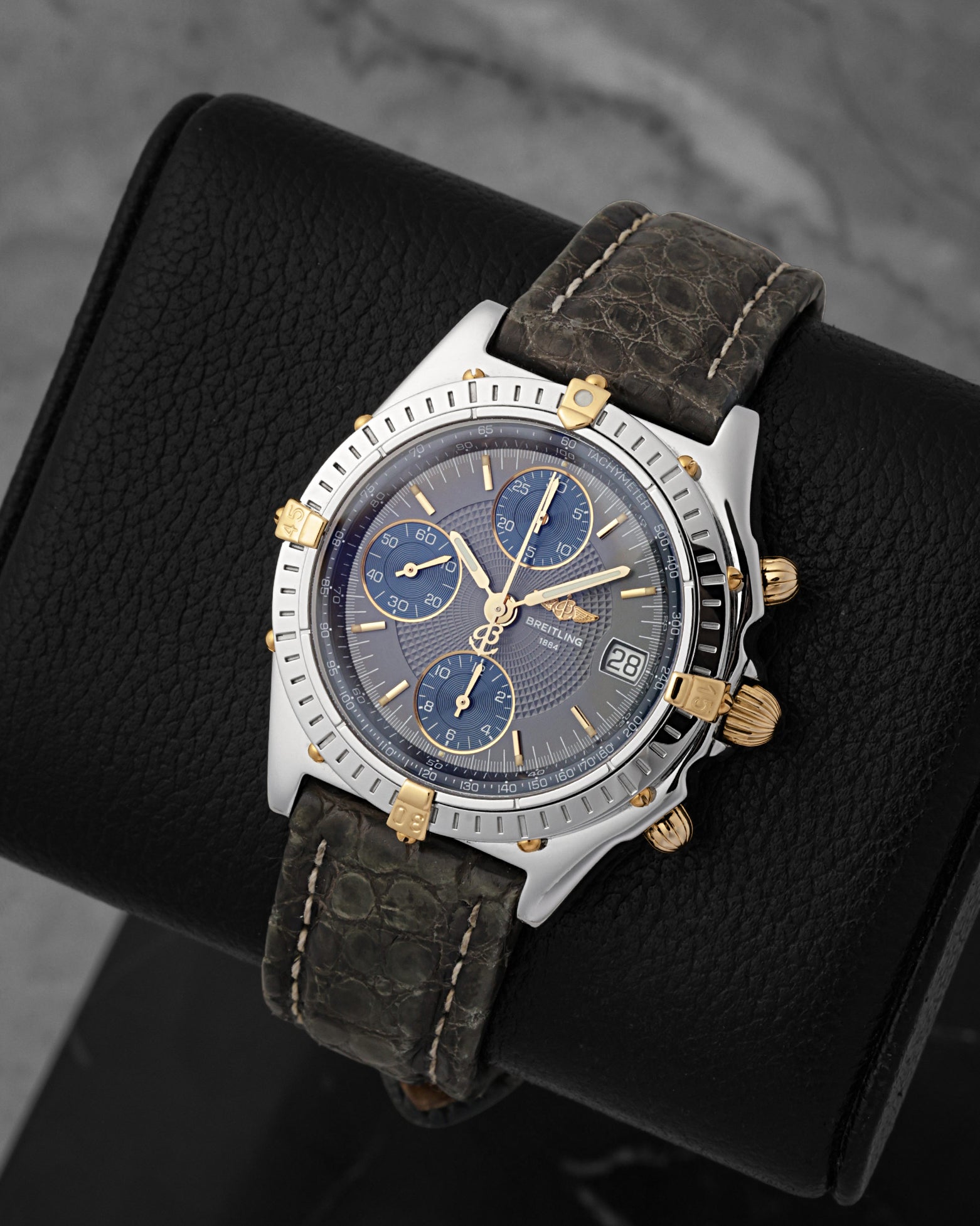 A three-quarter high-angle studio view of the 39mm neo-vintage Chronomat case displaying its signature unidirectional timing bezel accented with solid yellow gold 15-minute rider tabs