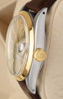 Close-up right profile view of the watch head highlighting the high-dome vintage acrylic Plexiglass crystal, the smooth gold bezel, and the fluted yellow gold Twinlock winding crown