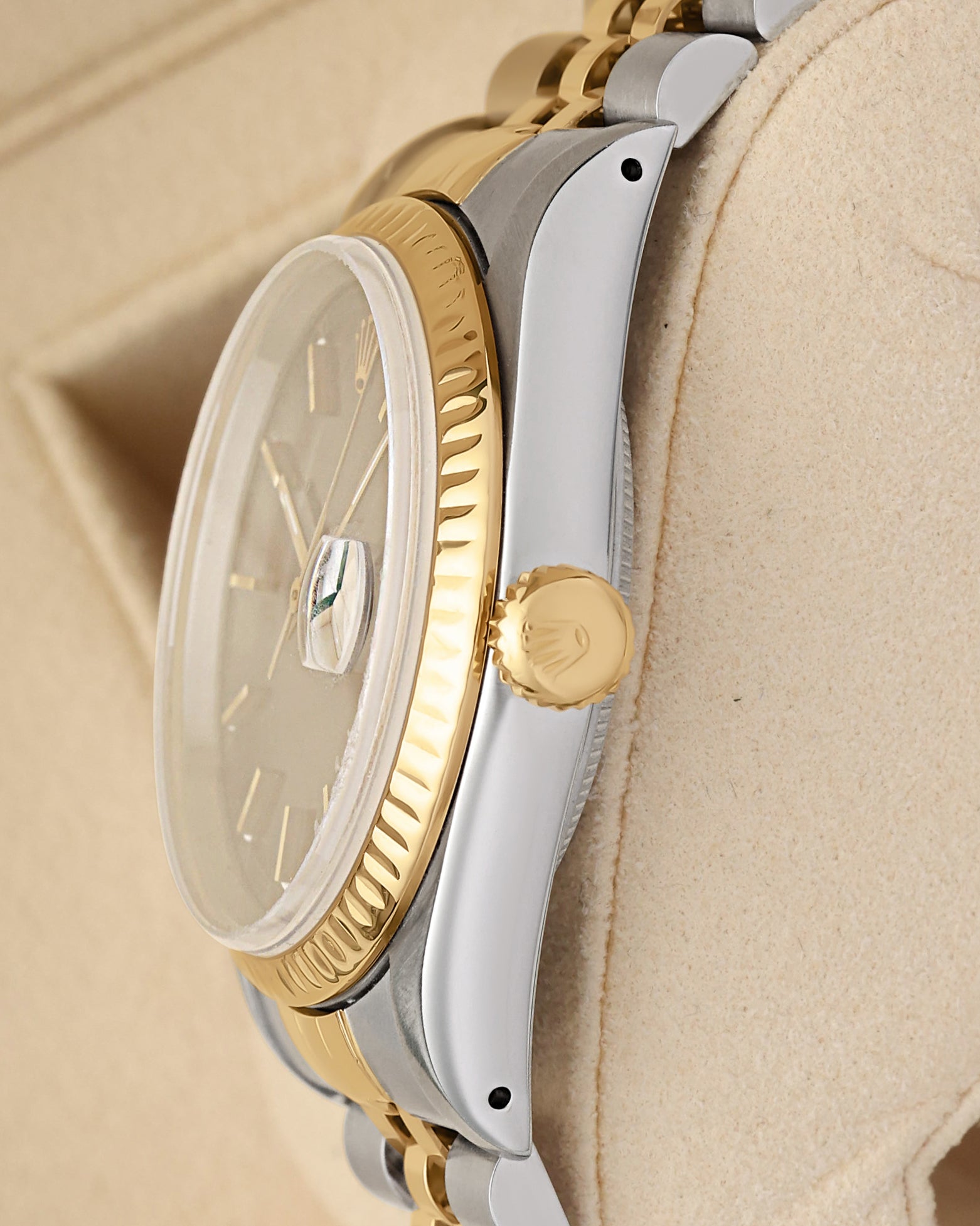 Close-up right profile view of the 36mm watch head highlighting the flat scratch-resistant sapphire crystal with magnified Cyclops lens and the fluted yellow gold winding crown