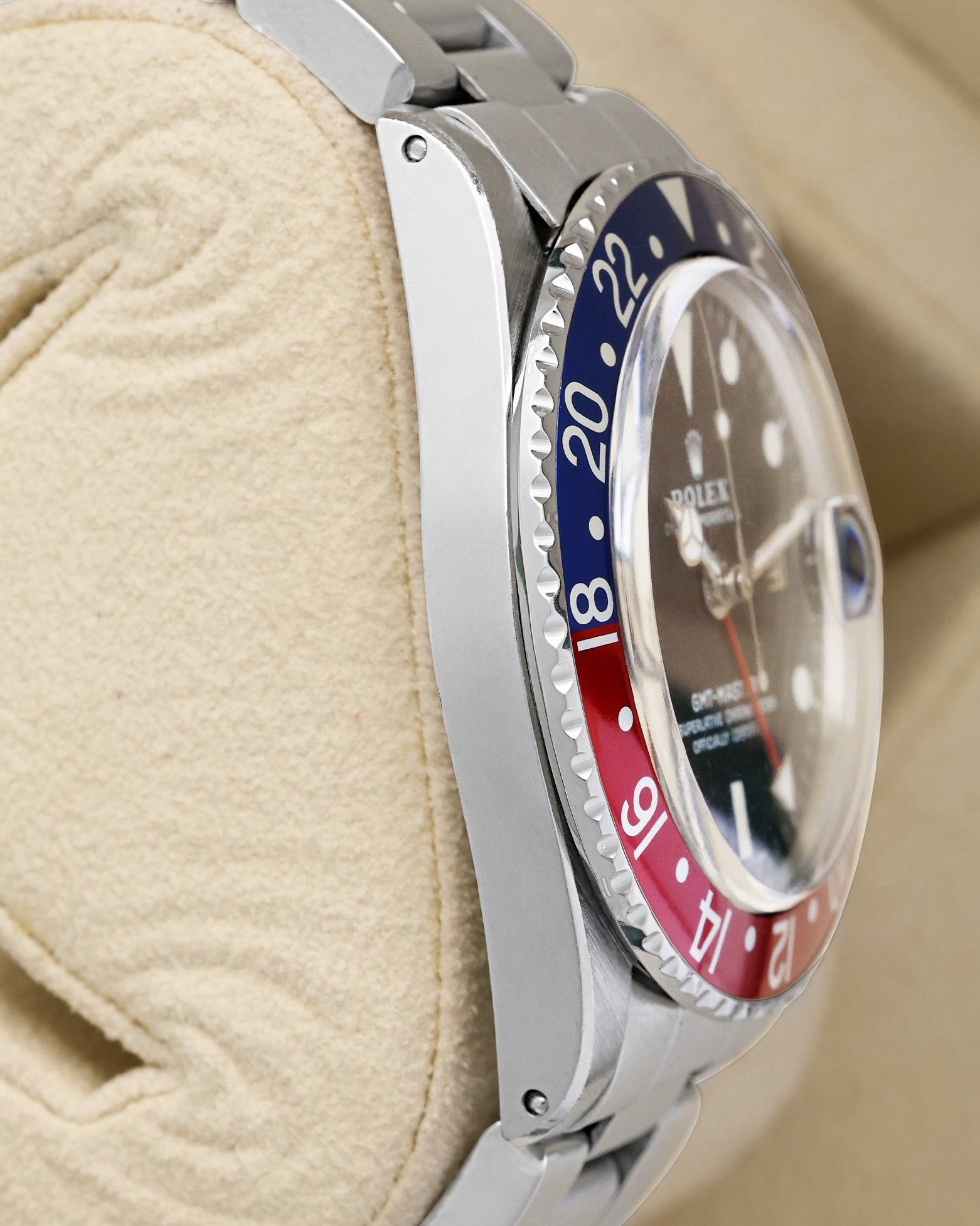 left-side case profile view of a vintage 40mm stainless steel Rolex Oyster case with a thin Pepsi bezel profile resting on a cushion