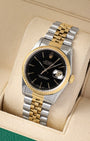 studio portrait of the 36mm two-tone luxury watch case showcasing its 18k yellow gold fluted bezel and gold center Jubilee links on a beige cushion