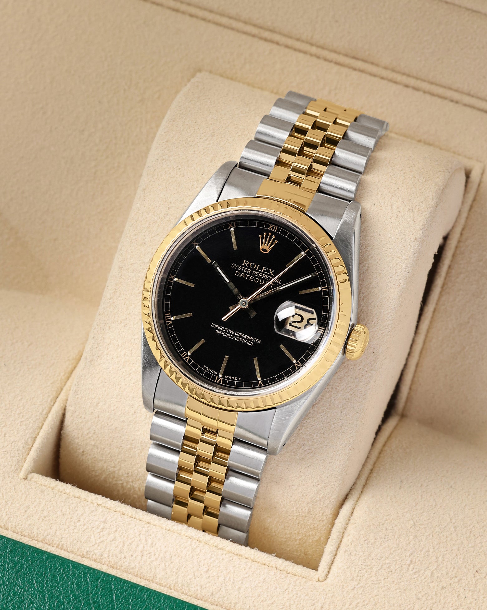 studio portrait of the 36mm two-tone luxury watch case showcasing its 18k yellow gold fluted bezel and gold center Jubilee links on a beige cushion