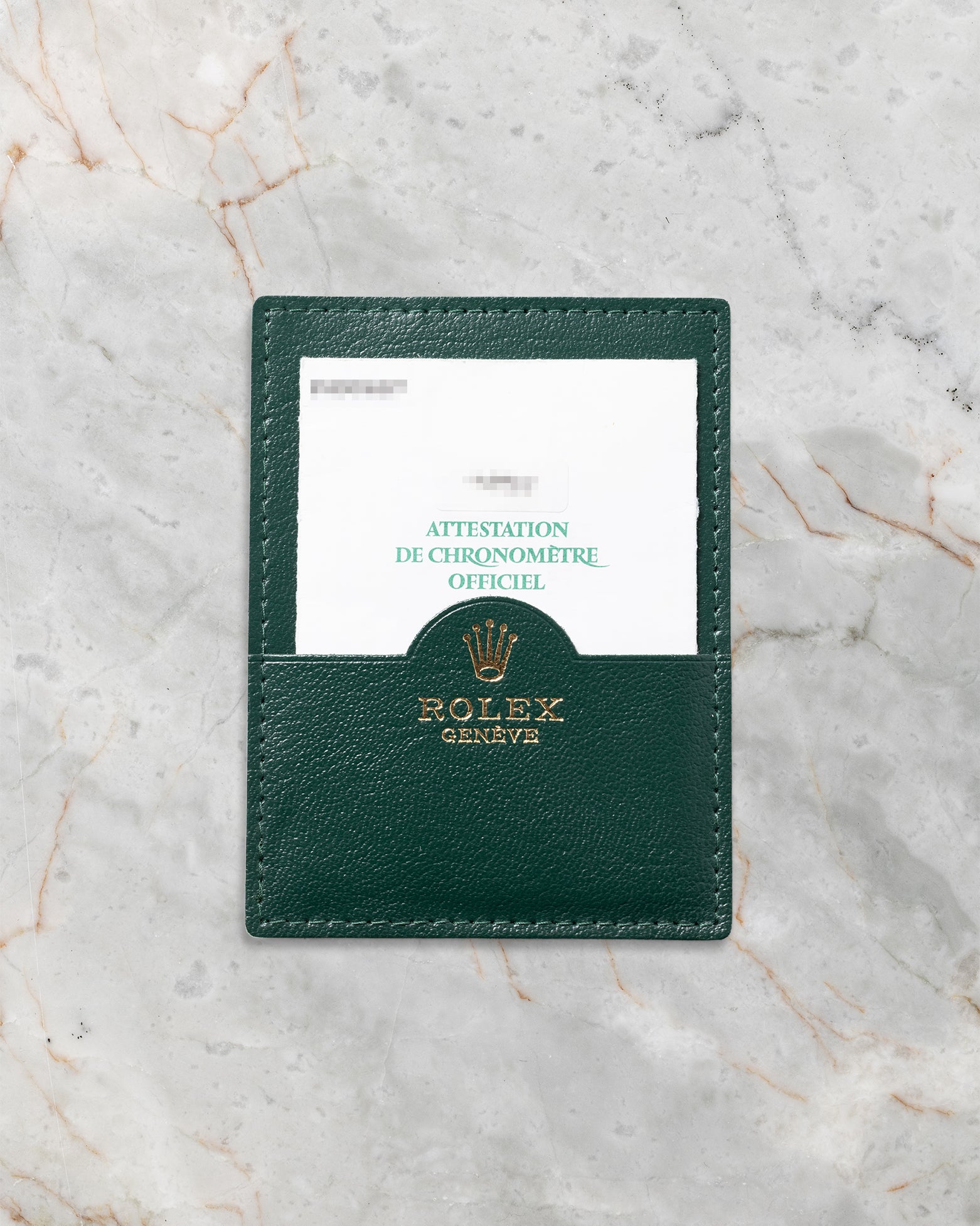 The official green Rolex pebble-grained leather document wallet displaying a factory booklet insert flat on a marble surface